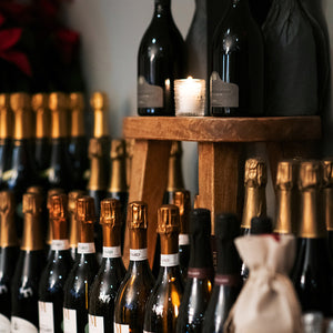 Wine bottles displayed on a wooden shelf with a candle in the background.
