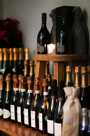 Wine bottles displayed on a wooden shelf with a candle in the background.