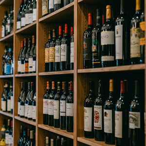 Wooden shelves filled with various wine bottles in a store or cellar setting.