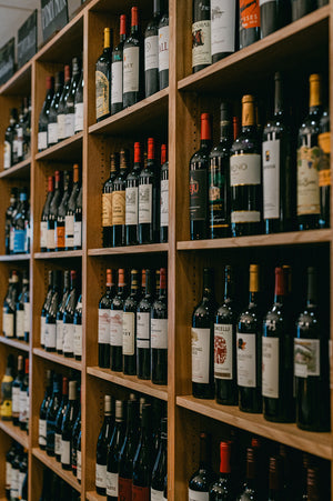 Wooden shelves filled with various wine bottles in a store or cellar setting.