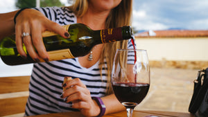 a woman pouring glass of red wine 